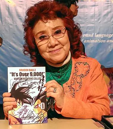 Masako Nozawa holds a signed copy of 'It's Over 9,000!'